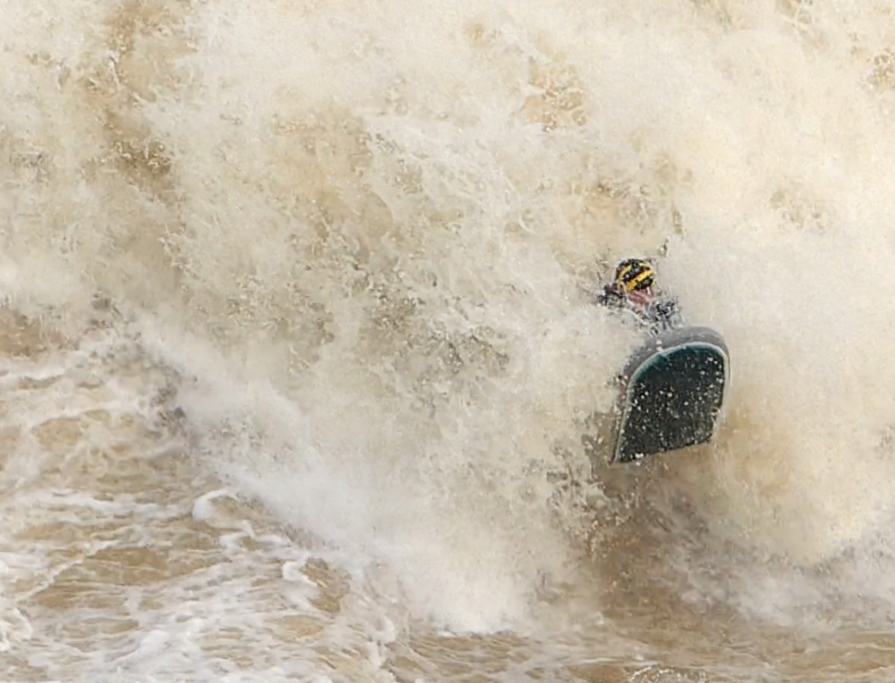 Riverboarder surfing a massive whitewater wave