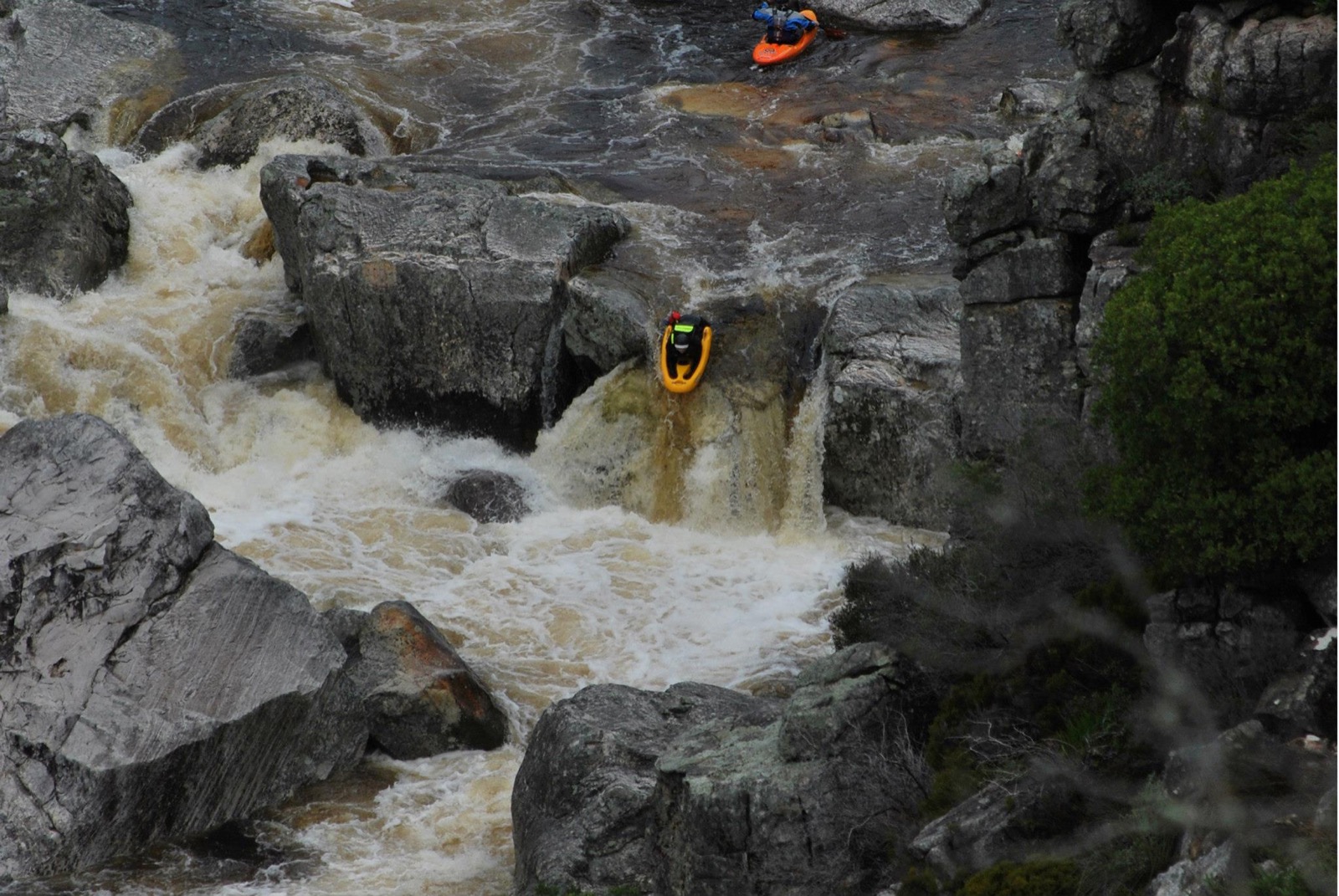 Riverboarders descending a steep rocky gorge rapid