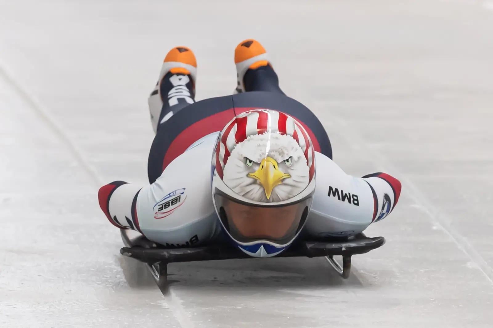 Katie Uhlaender headfirst on her skeleton sled, coming straight at the camera in a white helmet painted as an eagle's head