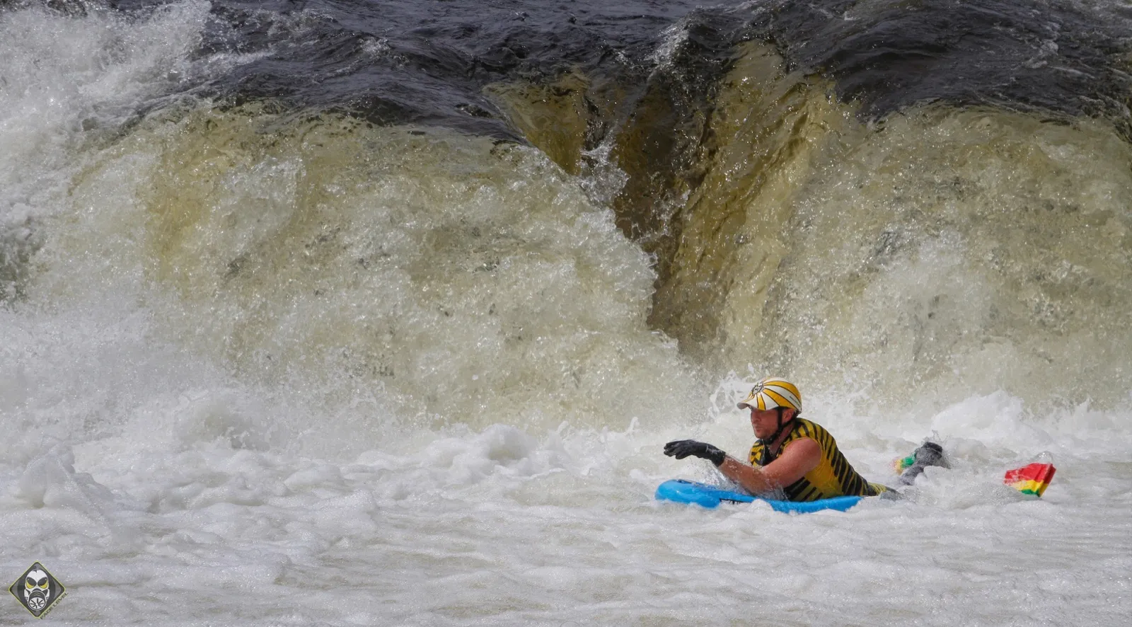 Josh Galt riding a flat foam riverboard in the boil below a large waterfall